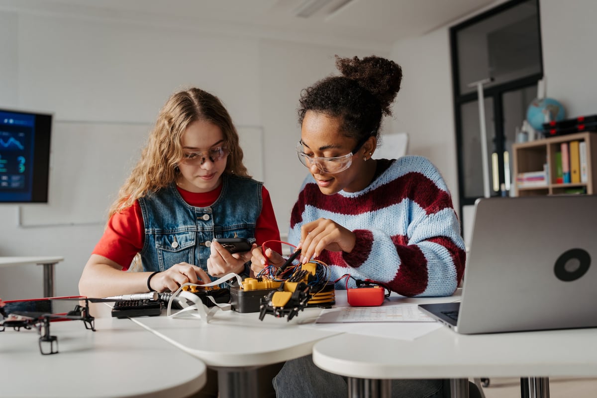 High school students, including girls, collaborating on a robotics project during a hands-on science class