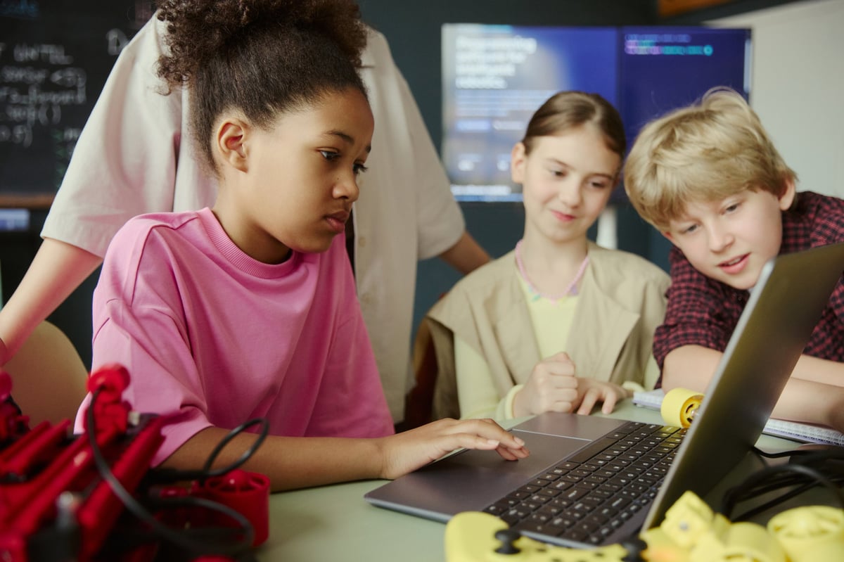 An African American student coding on a laptop during a classroom activity with classmates — learning digital skills together